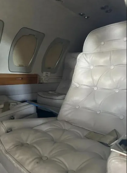 Another view of the aircraft's interior cabin, showing light gray tufted leather seats and windows.