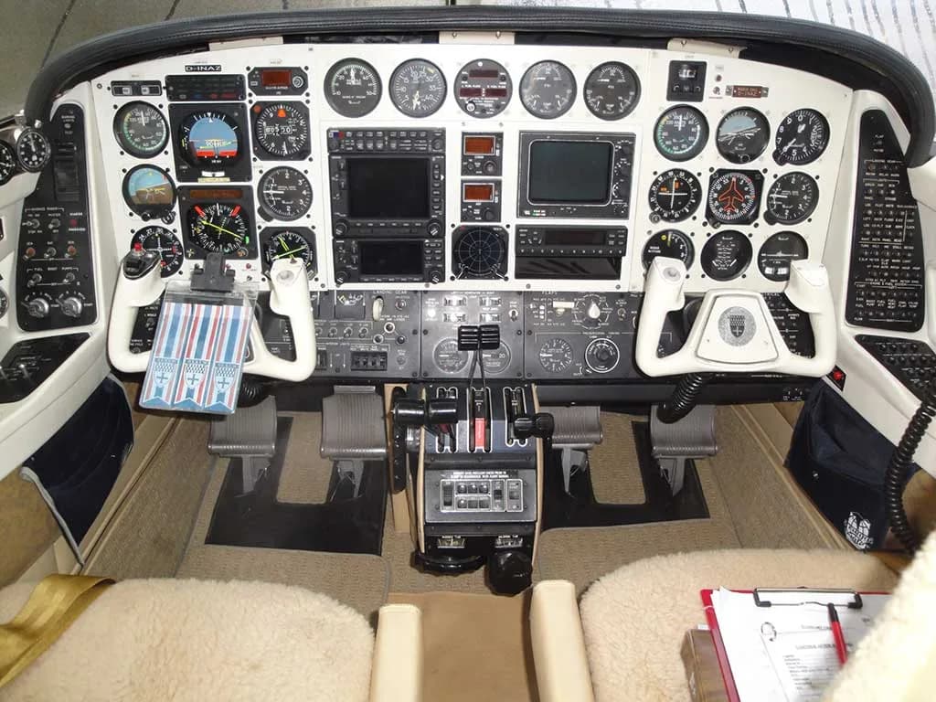 A wide view of the aircraft cockpit showing the instrument panel, dual control yokes, and throttle quadrant.