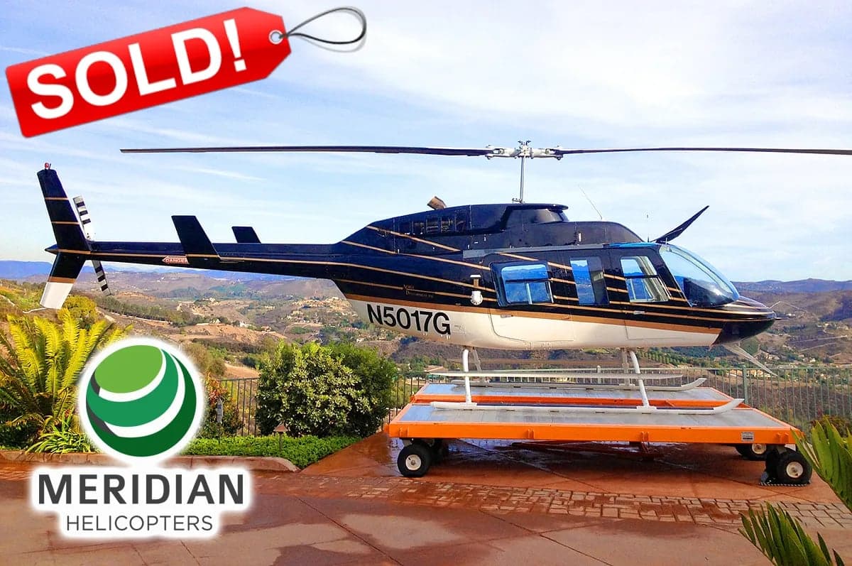 A black and white Bell 206 helicopter with tail number N5017G is shown on a trailer with a SOLD banner.