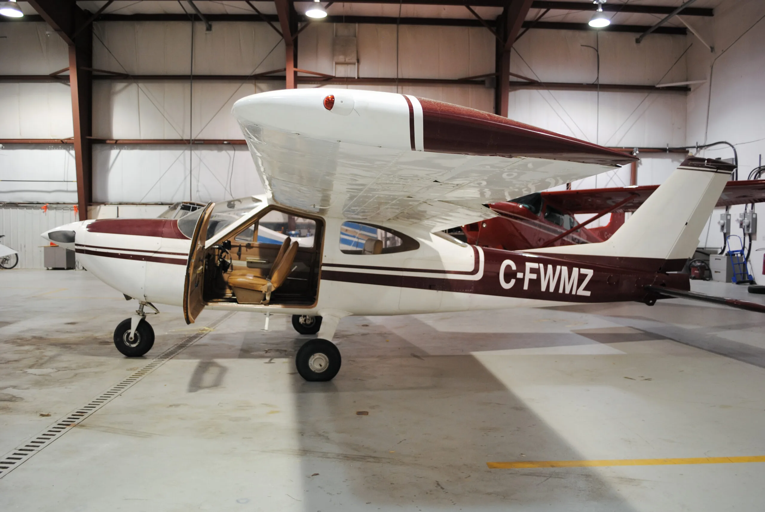 Side view of a Cessna 177 Cardinal with the door open, showing the registration C-FWMZ.