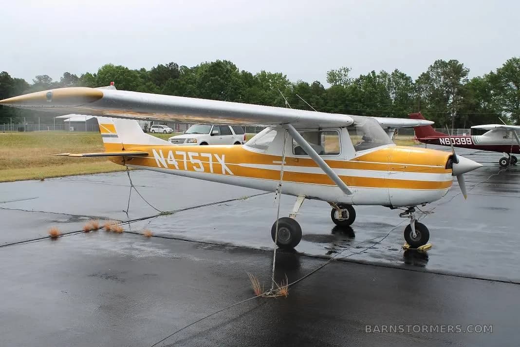 A yellow and white Cessna 150 (N4757X) is parked on a wet tarmac, viewed from the side.