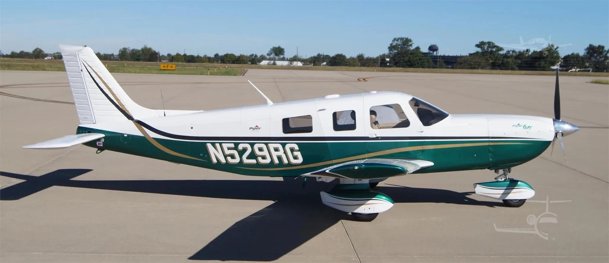 A side profile view of the white and green Piper 6XT (N529RG) parked on an airfield.