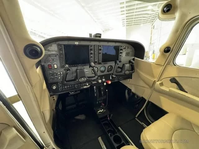 The cockpit of a small aircraft features a modern glass panel display and dual yokes.