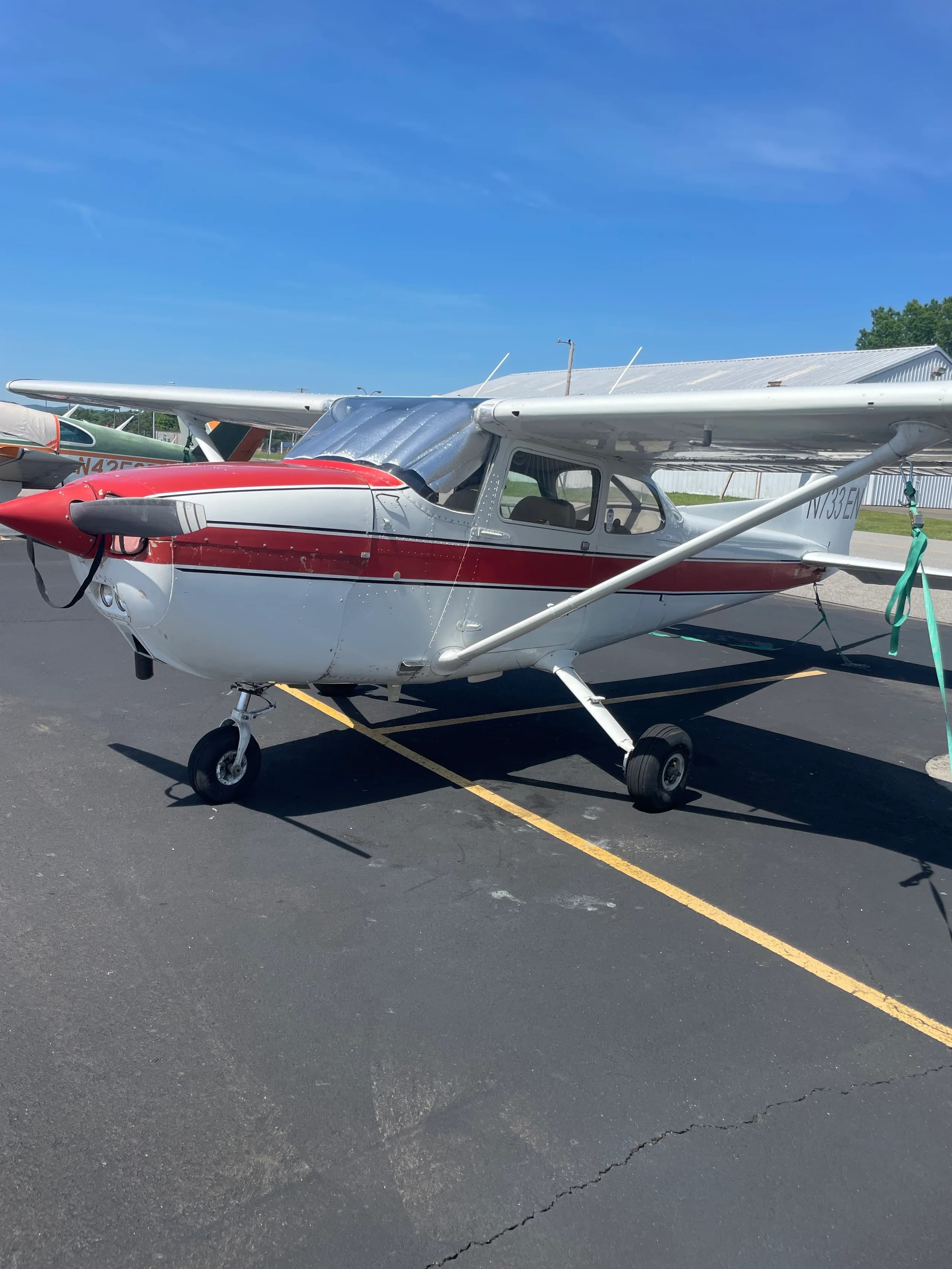 A white and red Cessna 172, registration N733EN, parked on an asphalt ramp on a sunny day.