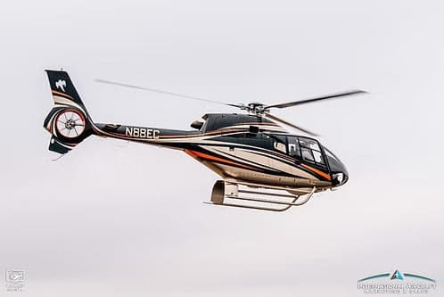 A black and silver Airbus helicopter, registration N88EC, in flight.
