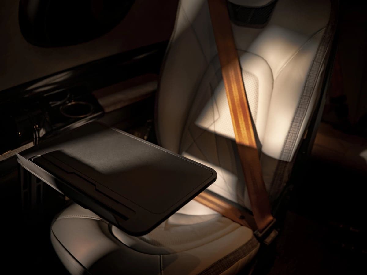 A Cirrus aircraft seat with a tray table and brown seatbelt.