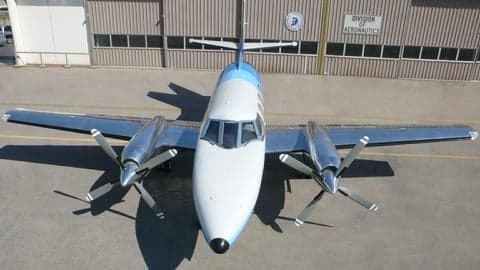A Beechcraft Baron with a blue and white paint scheme parked on the tarmac.