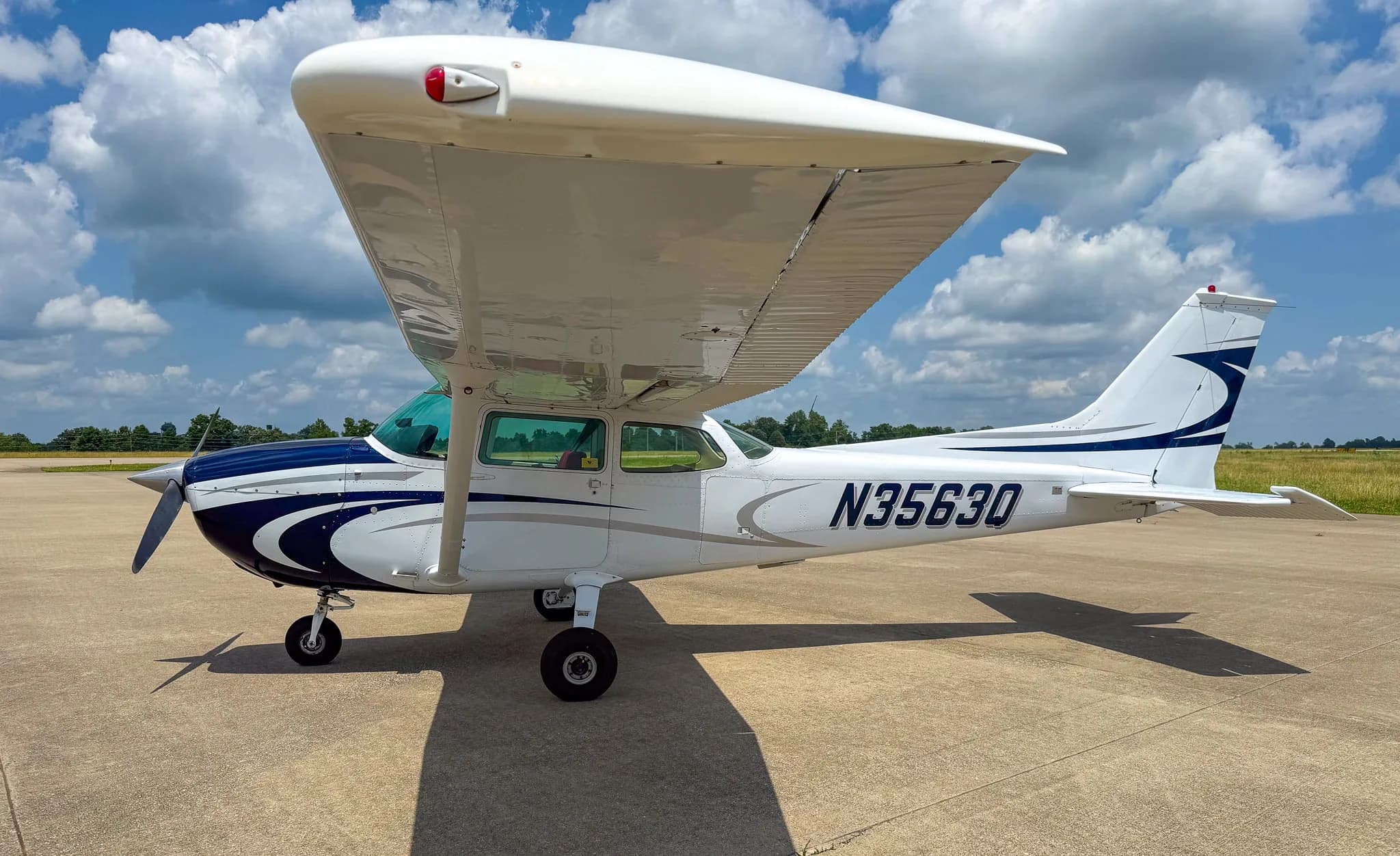 Left side view of a white and blue Cessna 172 with registration N3563Q on an airfield.