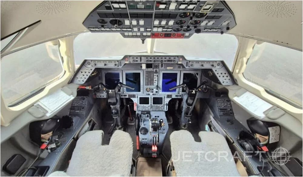 The cockpit of a business jet, showing the instrument panel, yokes, and overhead controls.