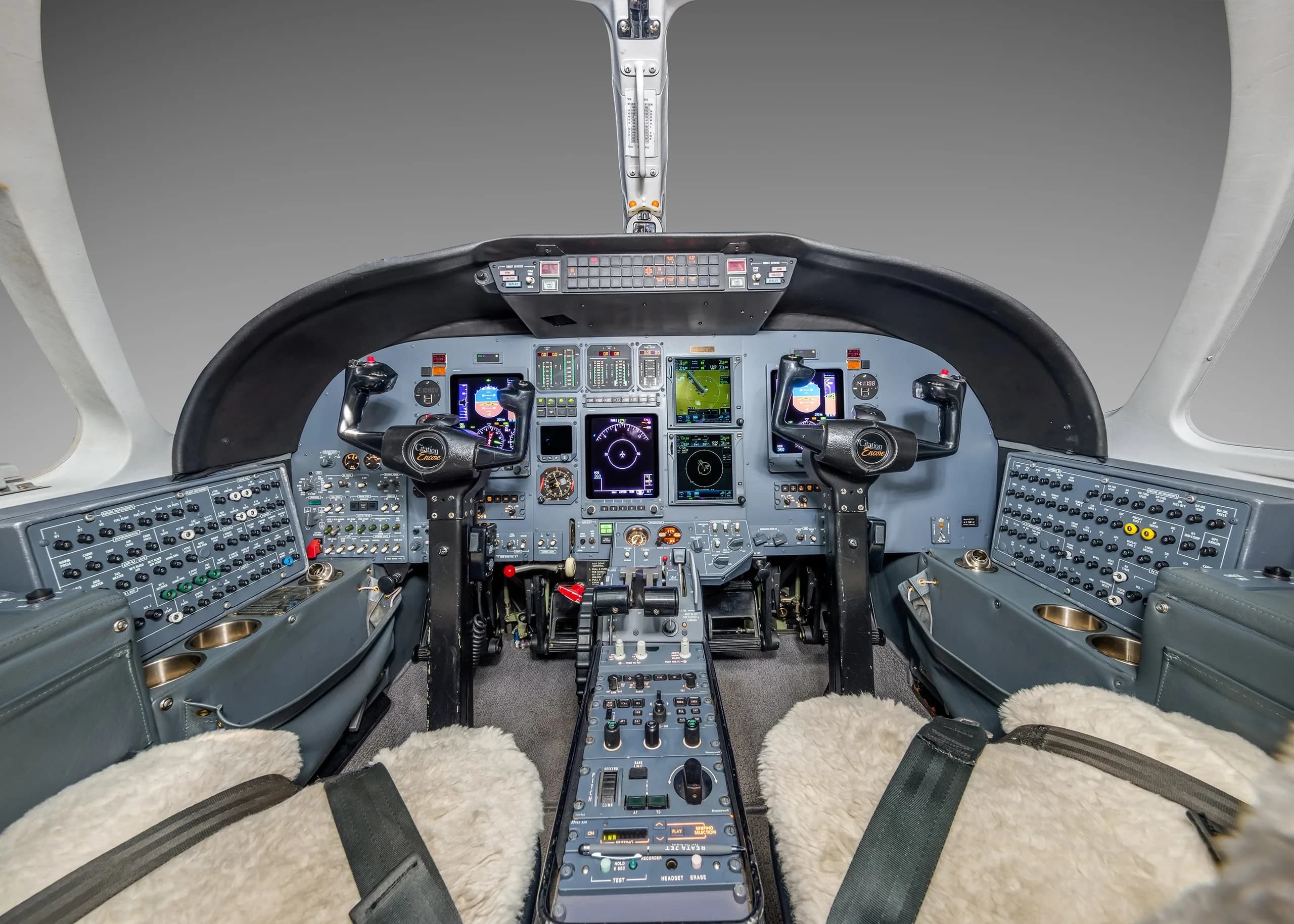 The cockpit of a business jet, showing the instrument panel, yokes, and throttle quadrant.