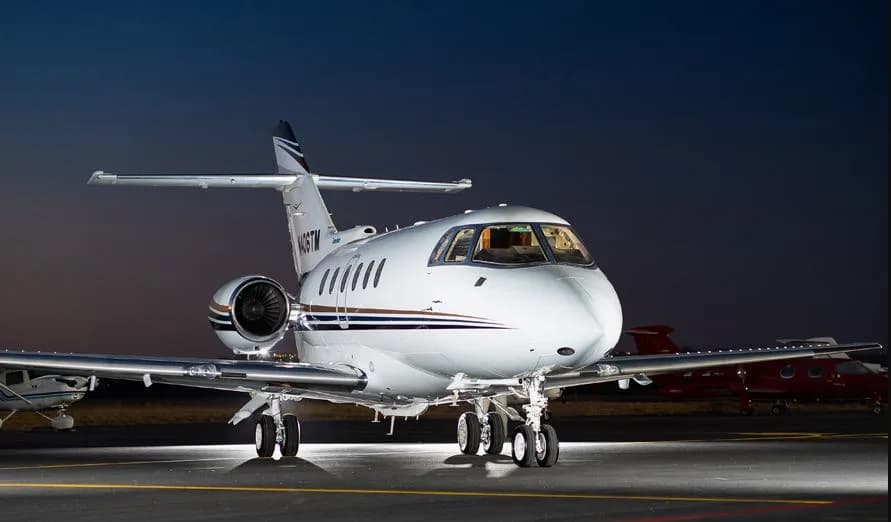 A Citation jet with tail number N406TM is parked on the tarmac at sunset.