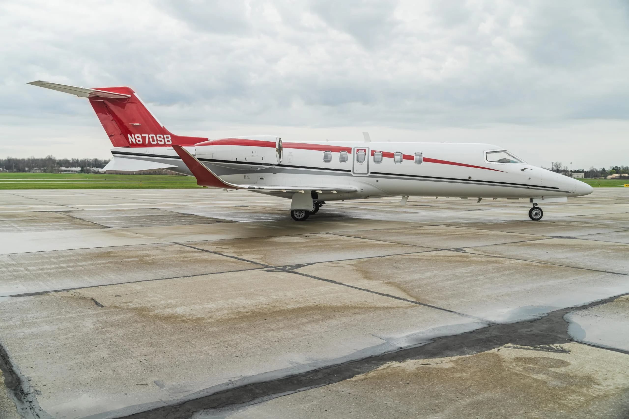 A Learjet aircraft with registration N970SB is parked on the tarmac with a red and white paint scheme.