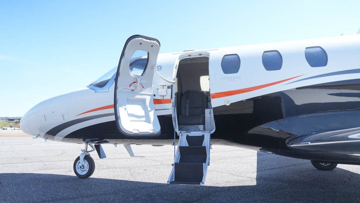 The aircraft's open door and steps are visible on the tarmac.