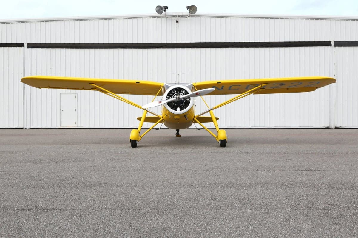 Front view of a yellow and white Stinson Reliant parked on the tarmac.