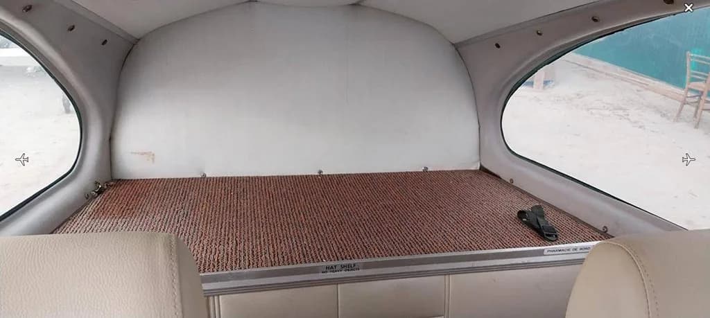 The rear cargo area or hat shelf of the aircraft cabin with a brown textured floor.