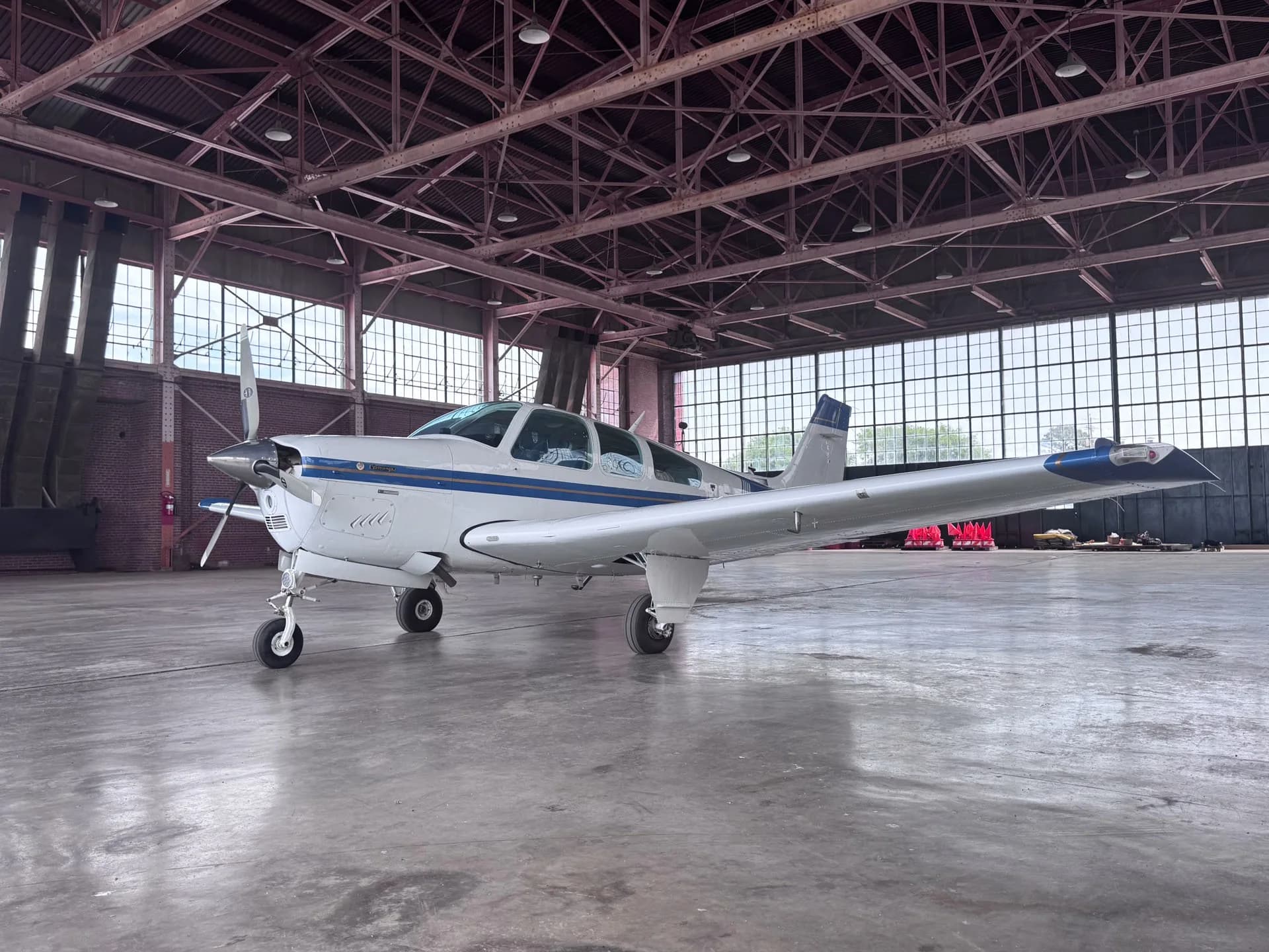A white and blue single-engine aircraft parked inside a hangar.