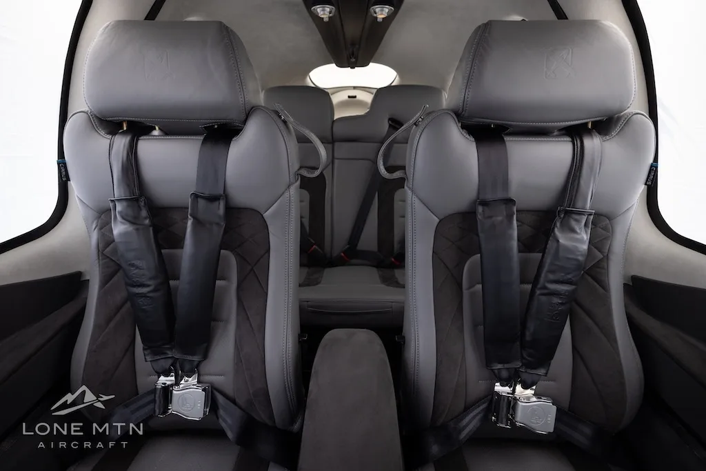 The gray and dark gray leather interior of the aircraft cabin, showing the front seats with seatbelts.