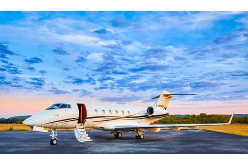 A white business jet with dark and gold stripes, registration N300NB, parked on a tarmac with its main cabin door open and stairs deployed.