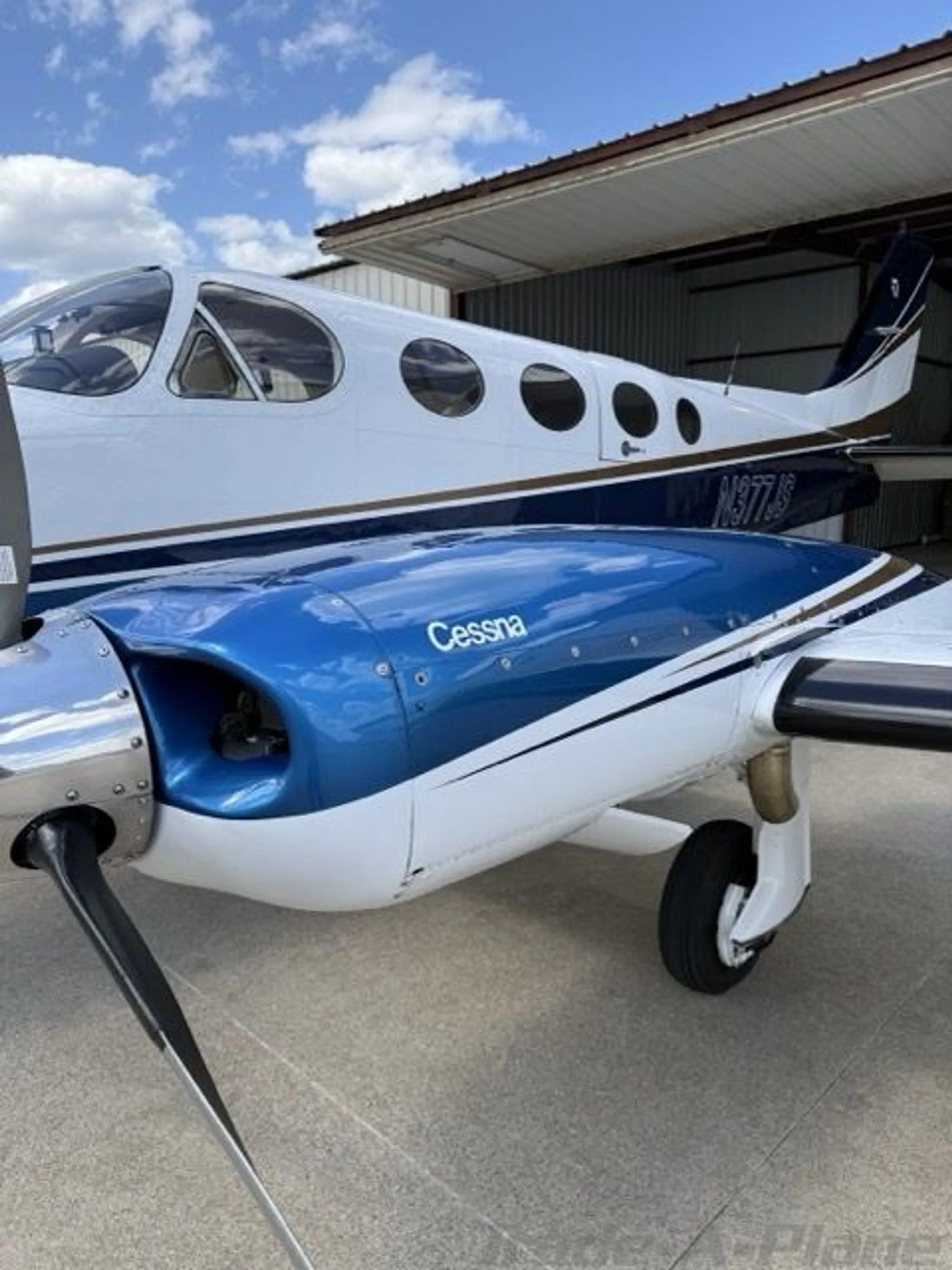 A close-up of the blue engine cowling with "Cessna" text and the white fuselage of the N377JS aircraft.