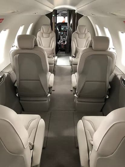 A view down the aisle of the aircraft cabin with seating and cockpit in the background.