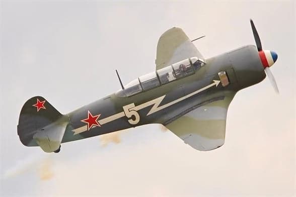 A Lavochkin La-9 in flight with a gray and green paint scheme and a red star on the tail.