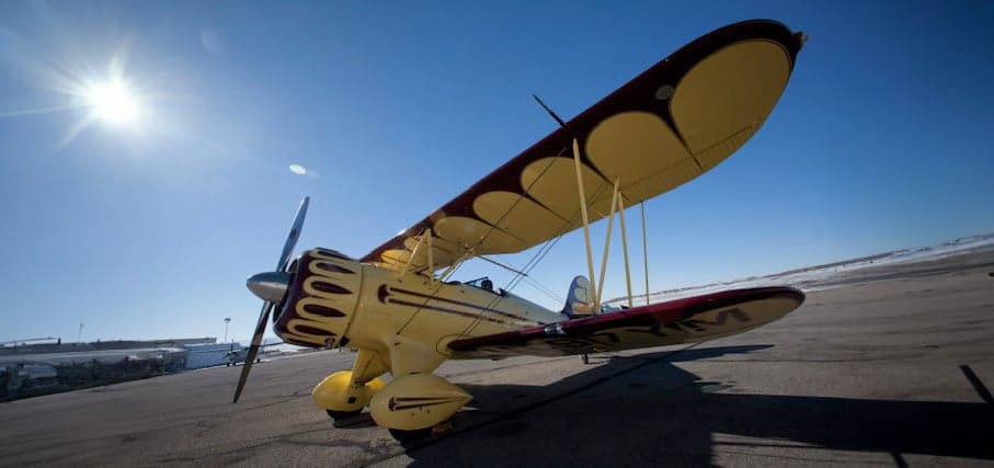 A yellow biplane with red accents parked on the tarmac.