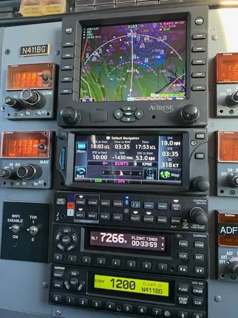 A detailed close-up of the avionics stack in the cockpit, featuring multiple navigation and communication displays, with N411BG visible on the transponder.
