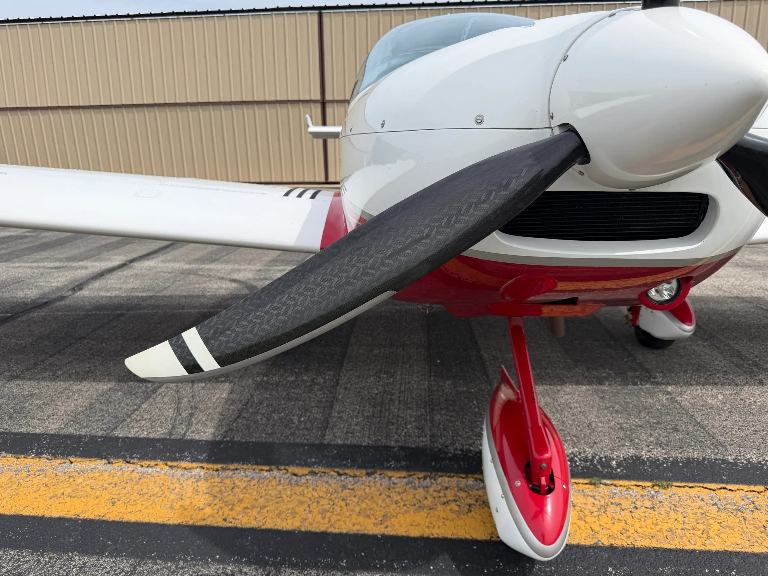 Close-up of the propeller and red and white nose landing gear of the SportCruiser aircraft.