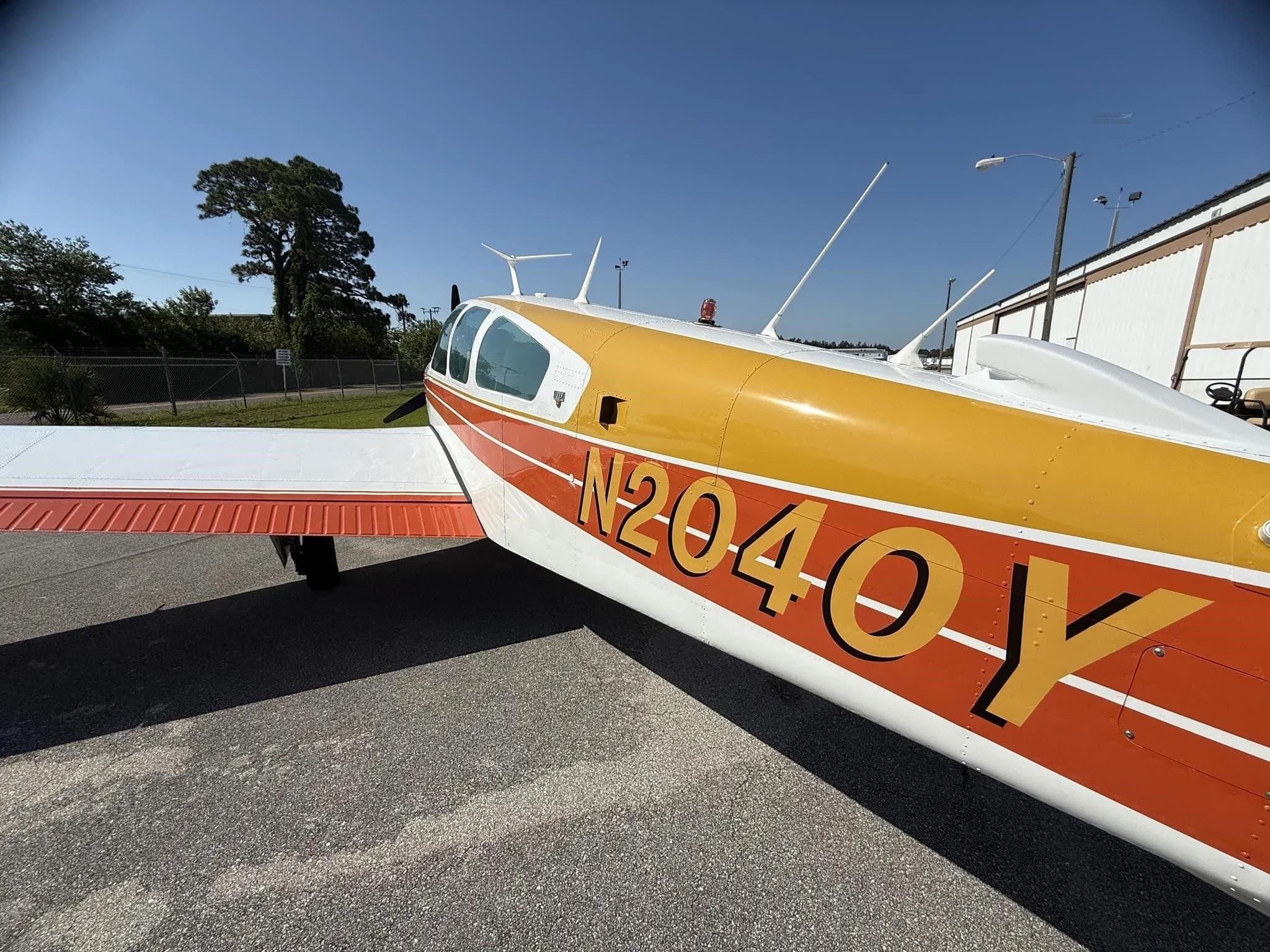 A close-up side view of the fuselage of a white and orange single-engine aircraft, N2040Y, showing the registration.