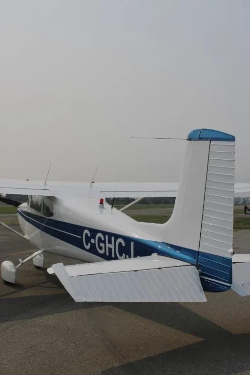 Rear view of a Cessna 172 with blue stripe parked on the tarmac.