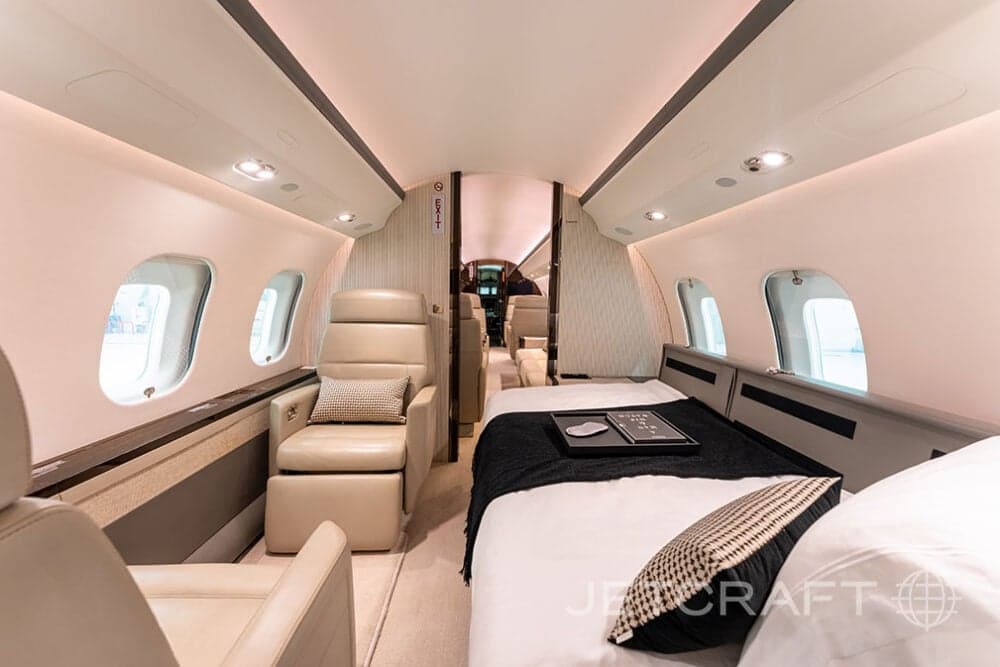 Interior view of a Bombardier Global Express business jet with beige leather seats and a bed.