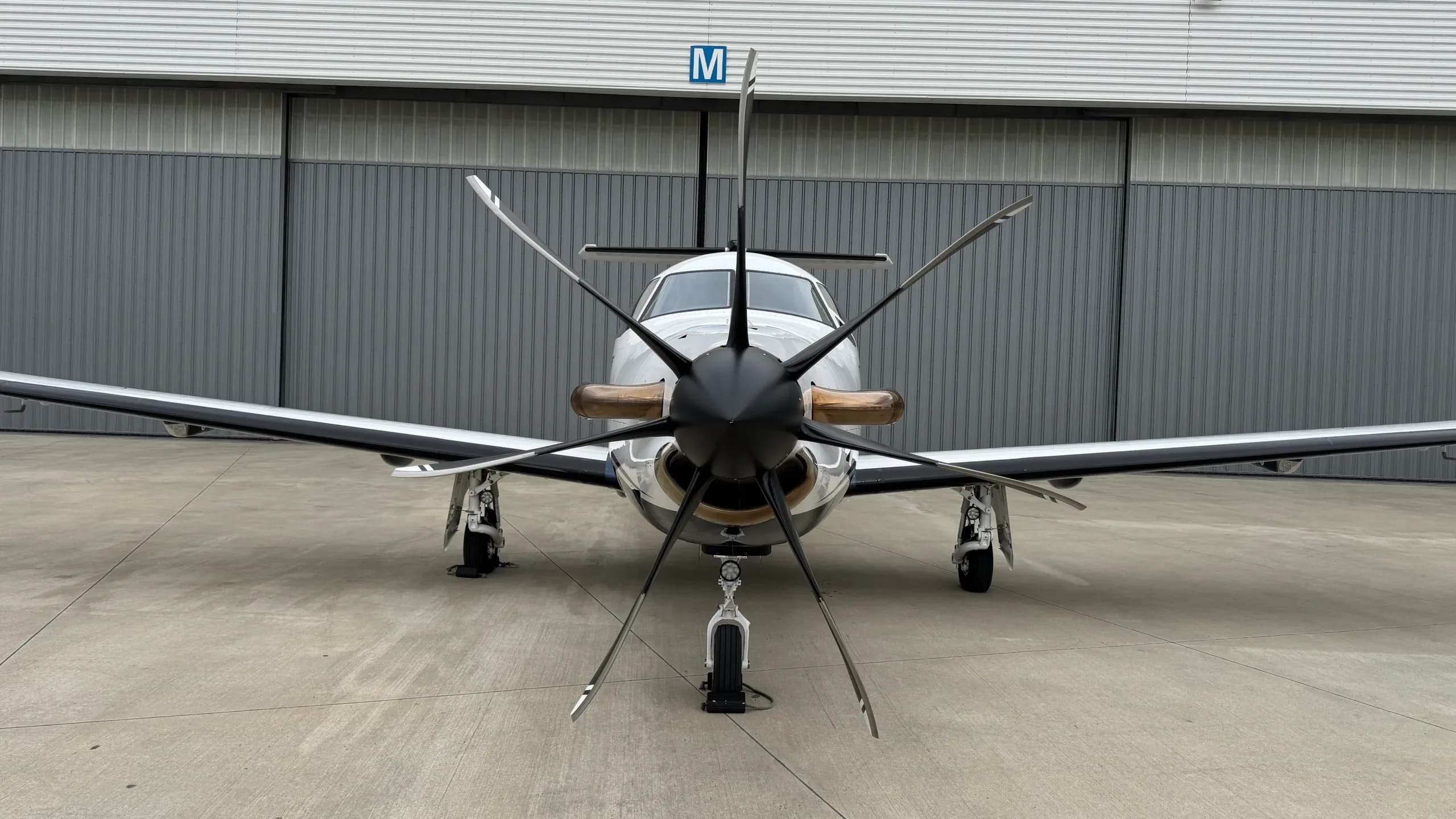 The modern glass cockpit of a Pilatus PC-12, featuring multiple display screens and sheepskin seat covers.
