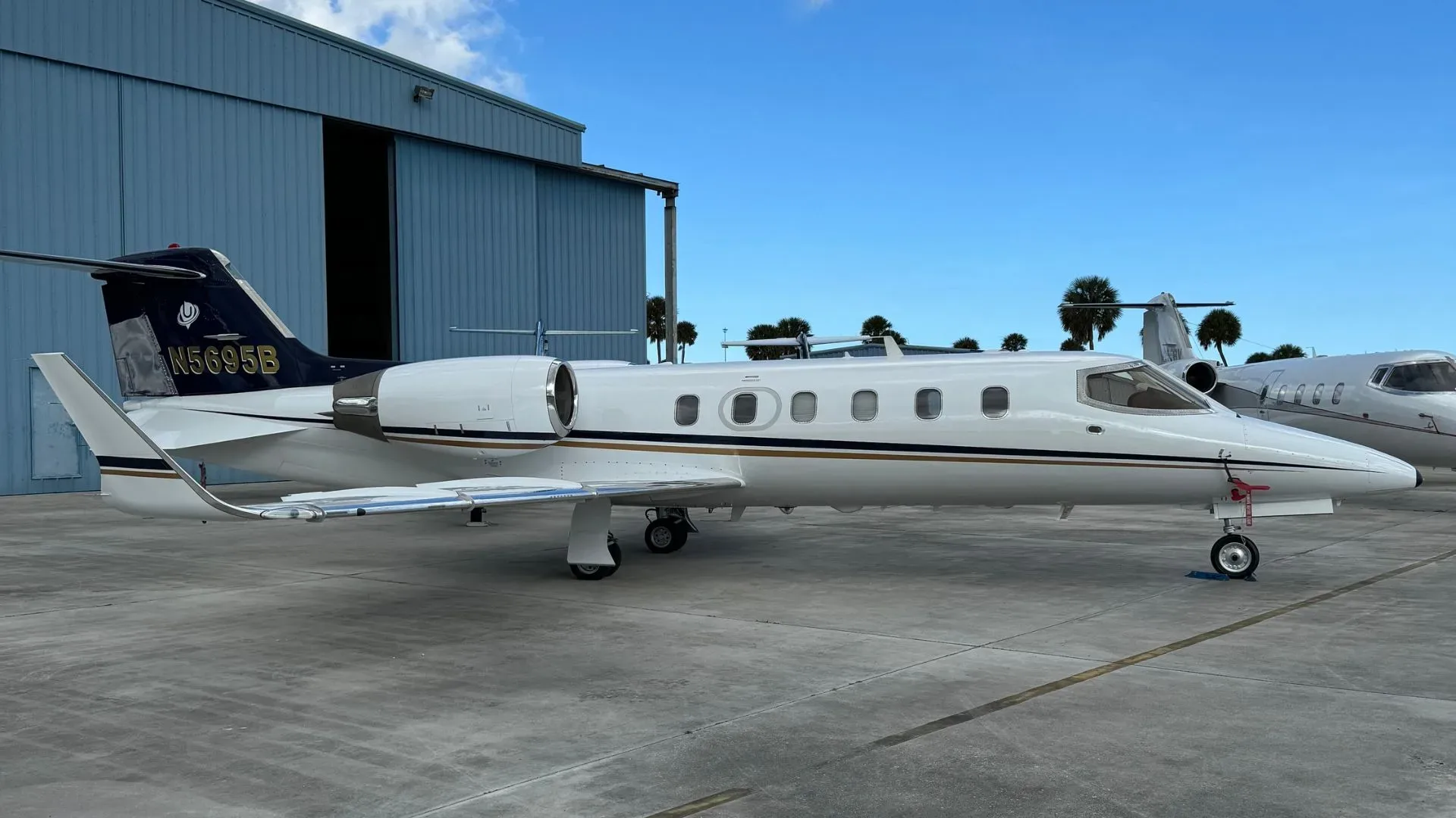 A Learjet 35A, registration N5695B, is parked on the tarmac in front of a hangar.
