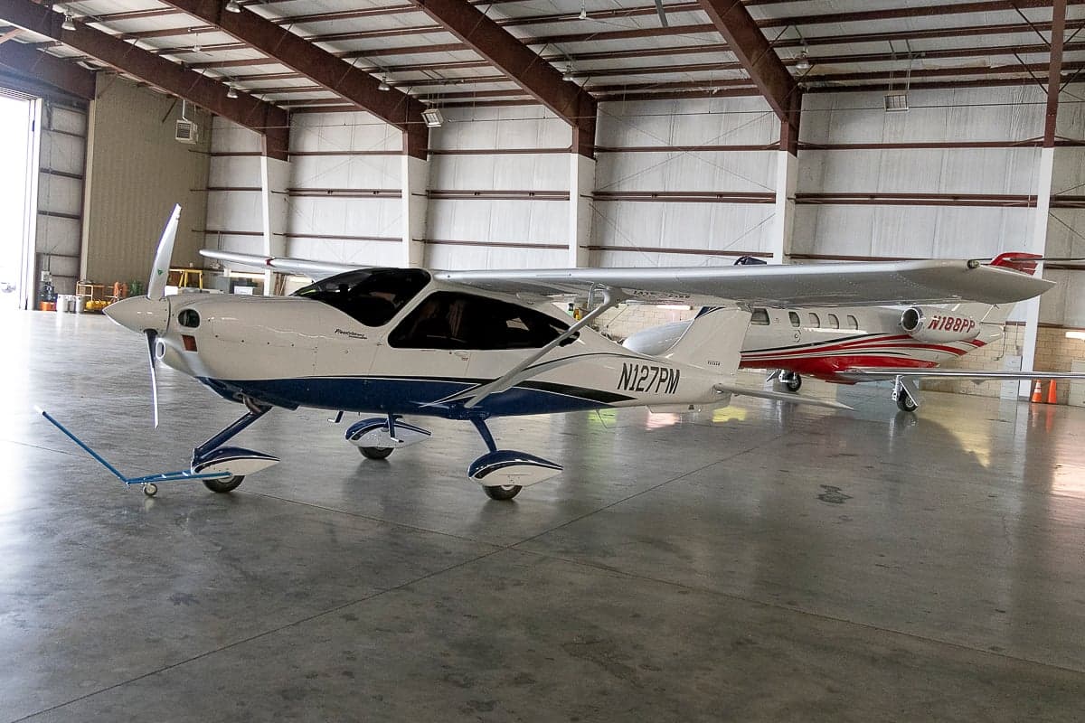 Tecnam P2010 aircraft with blue and white paint scheme in a hangar.