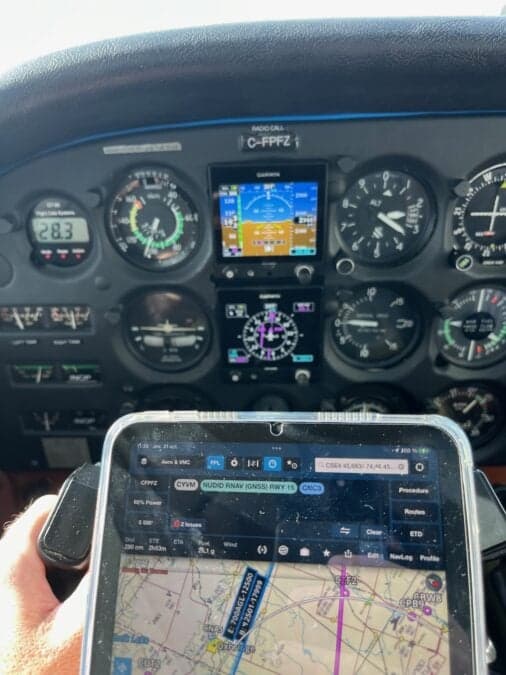 Cockpit view of the Cessna 210 HP aircraft C-FPFZ instrument panel with a tablet showing a map.