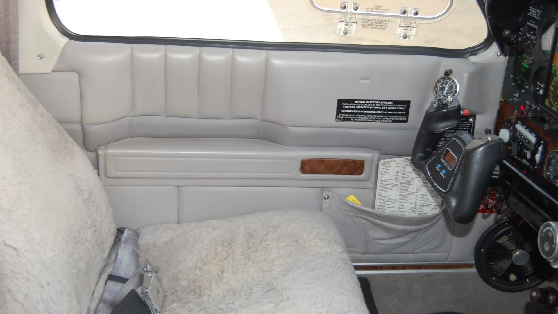 A view of the interior of the Beechcraft Bonanza, showing the side panel and pilot controls.