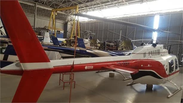 Side view of a Bell Jet Ranger helicopter with registration ZS-RDV inside a hangar.