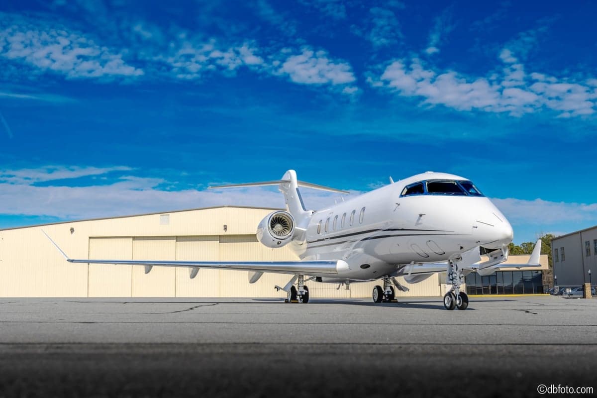 A front-quarter view of a white Bombardier Challenger business jet parked on an airport tarmac.