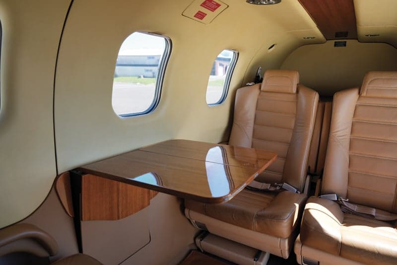 View of the aircraft cabin with a table and tan leather seats.