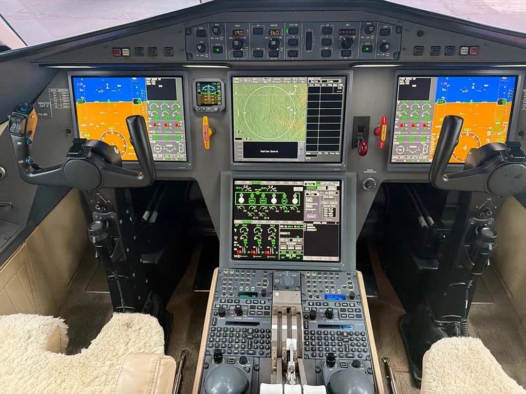 The modern cockpit of a business jet with multiple digital displays and control yokes.