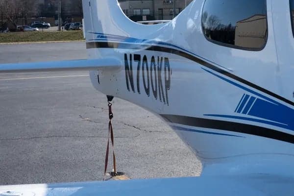 Close up of the tail of a white Cirrus aircraft with blue stripe, registration N700KP.
