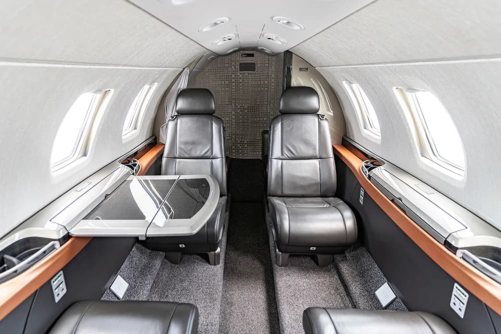 The aircraft cabin interior with dark leather seats and a deployed fold-out table between two seats.