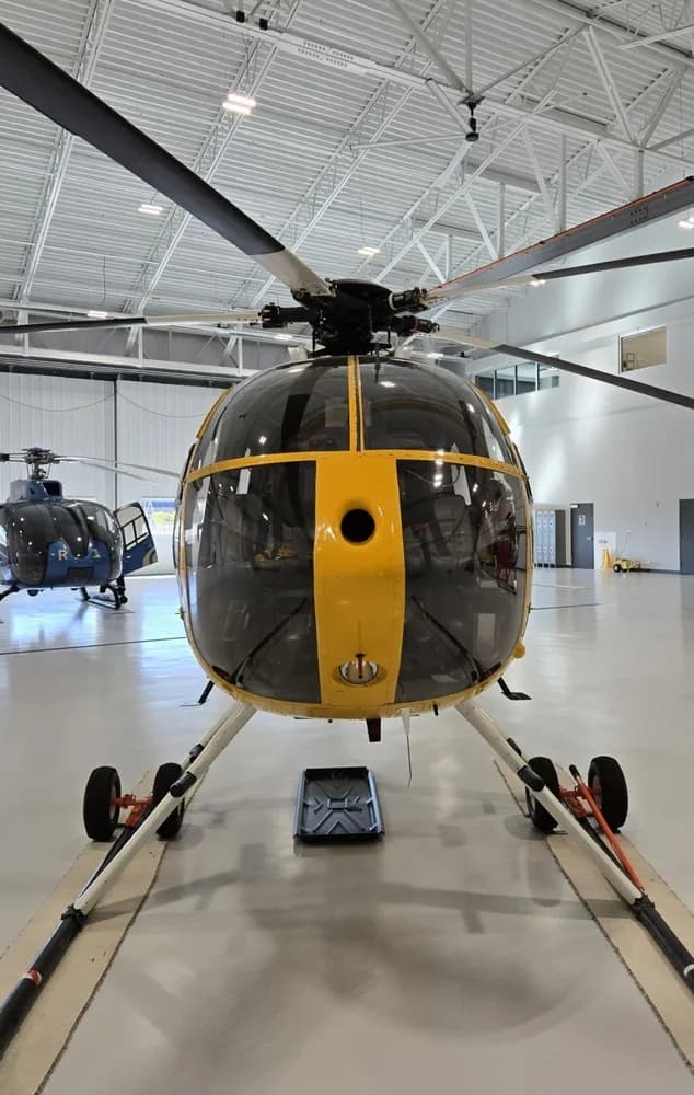 A head-on view of the yellow N64RS helicopter with its large front windows in a hangar.