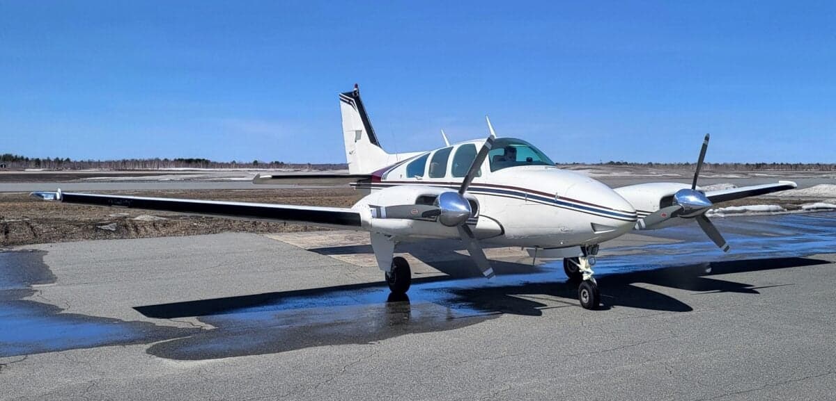 A Beechcraft Baron sits on the tarmac on a sunny day.