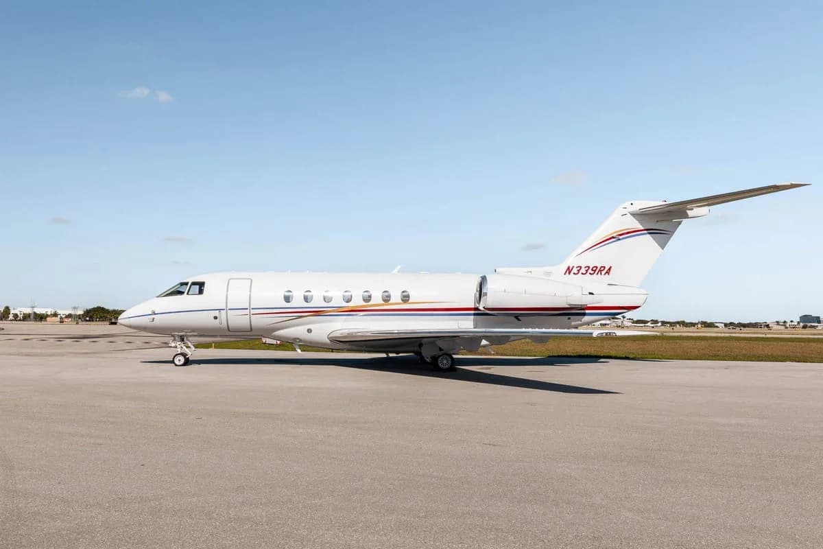 A white Hawker 800XP business jet with red and blue stripes, registration N339RA, parked on the tarmac from a slightly rearward angle.