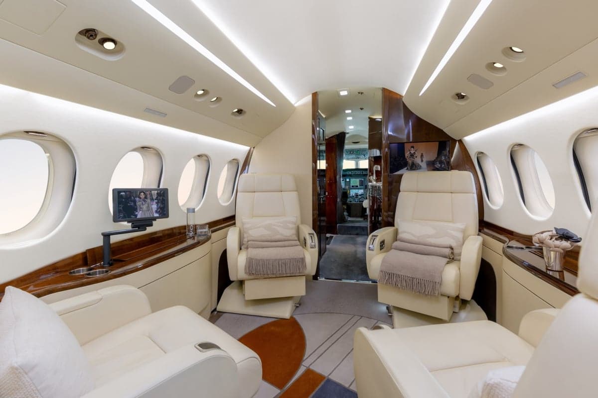 View of the aircraft interior with cream-colored seats and a central aisle.