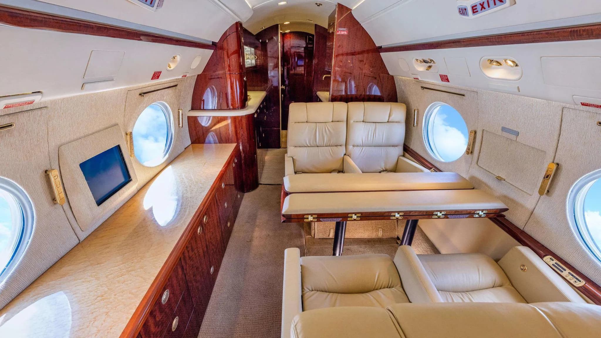 The spacious cabin interior of a Gulfstream G550, with a dining table and cream leather seating.