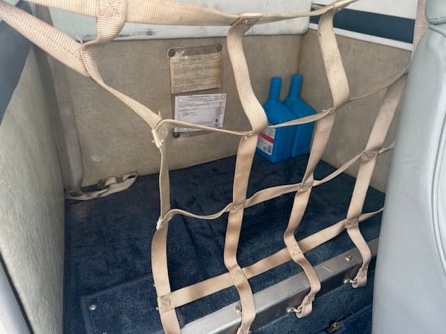 View of the aircraft's rear storage area with netting and supplies.