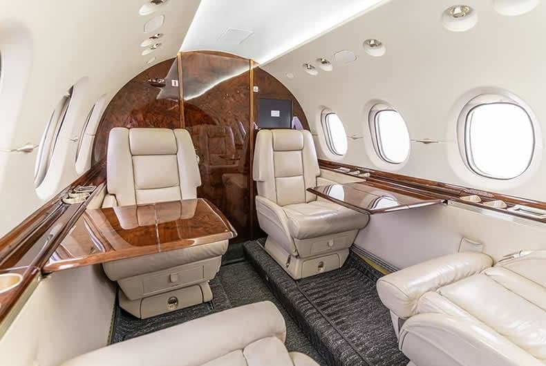View of the aircraft's interior with leather seats and fold-out tables.