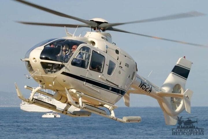 An EC135 helicopter in flight over the ocean.